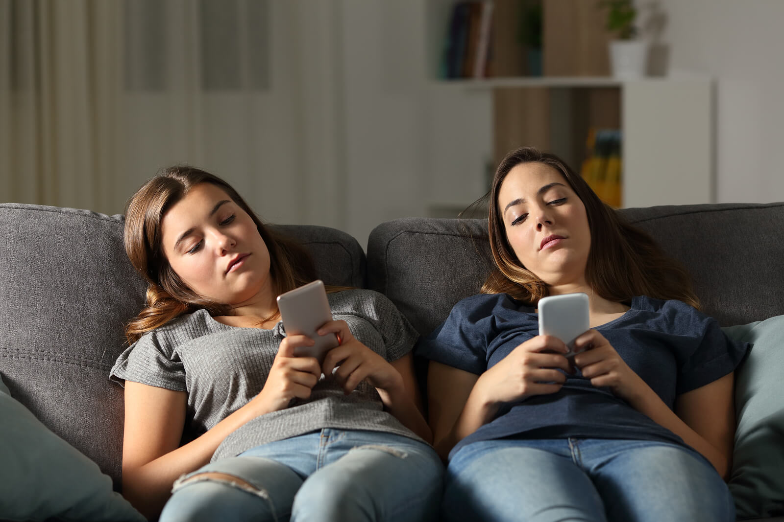 Adolescentes aburridas mirando el móvil sin hacer sus tareas.