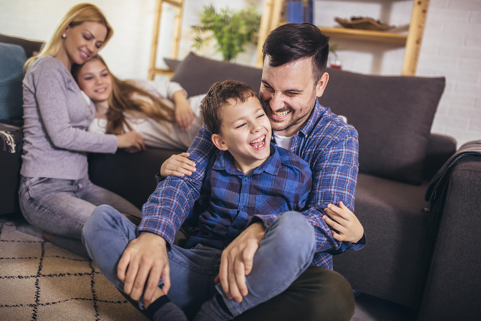 Padres jugando con sus hijos en el salón de casa para mostrar el apoyo familiar.