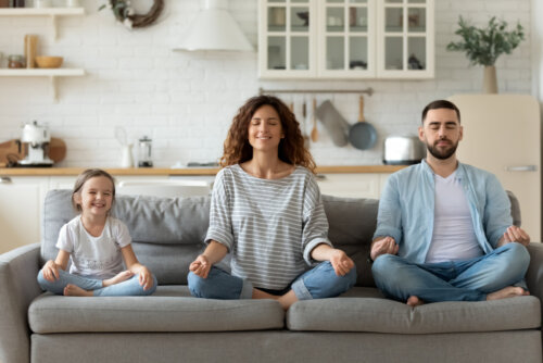 Familia realizando actividades de meditación y mindfulness en el sofá de casa.