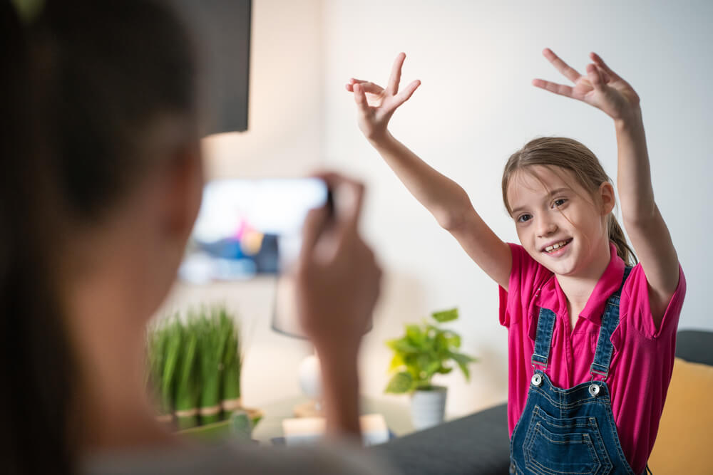 A mother recording a video of her daughter.