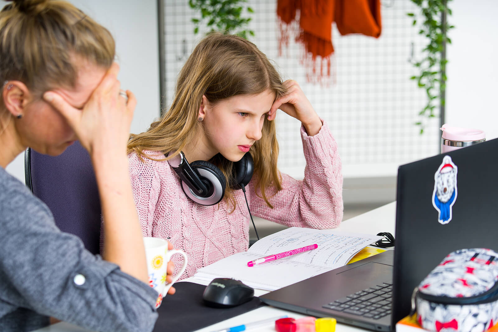 Chica adolescente junto a su madre haciendo deberes.