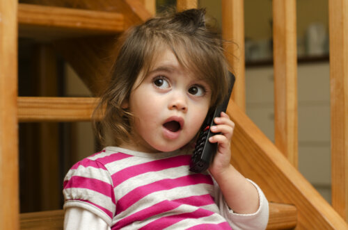 Niña pequeña haciendo que habla por teléfono ya que está en la etapa prelingüística e imita a sus padres.