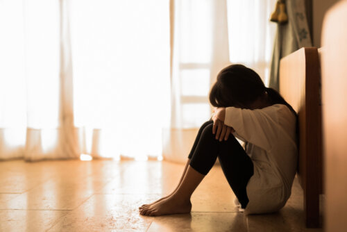 Niña sentada en el suelo triste.