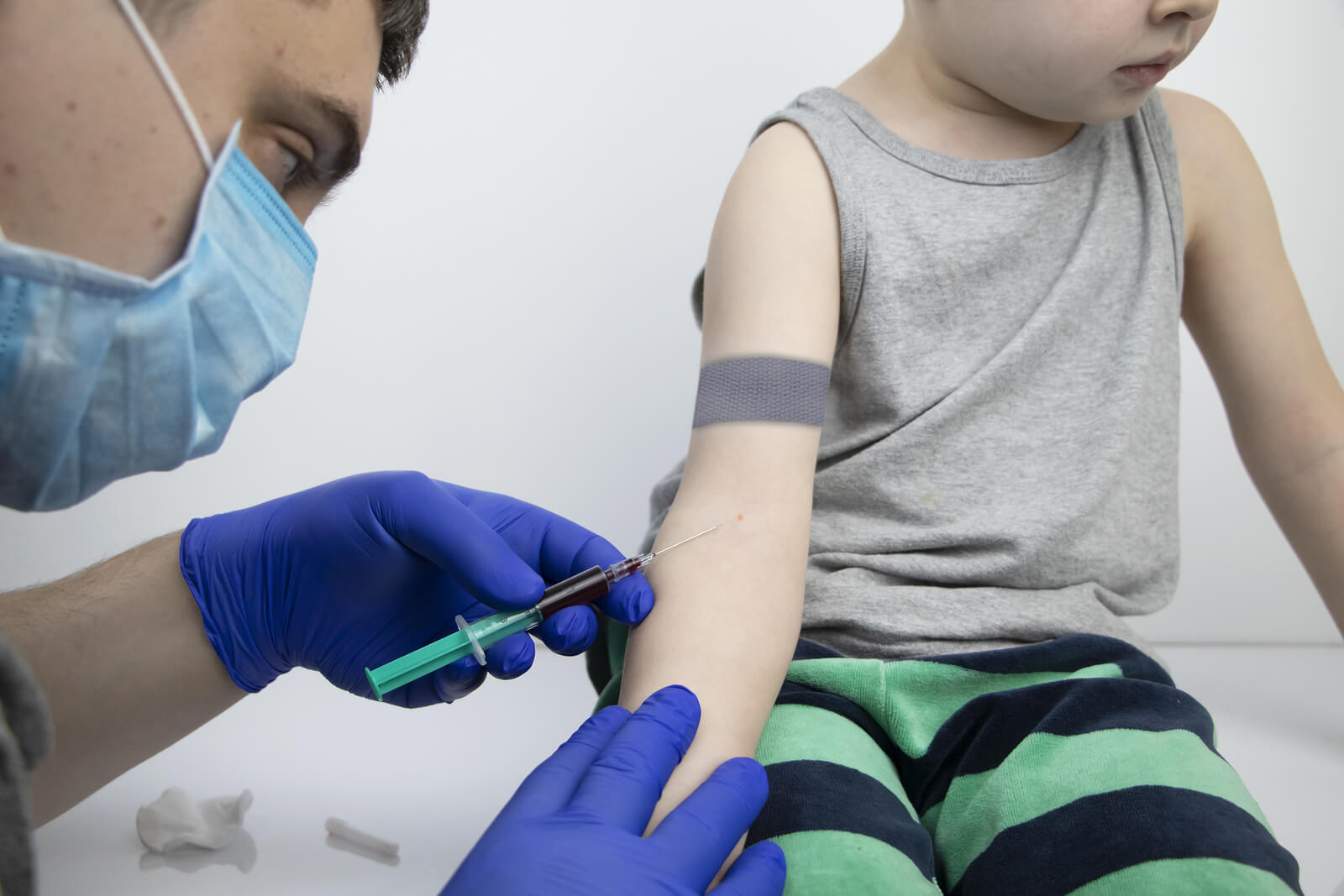 Médico haciendo un análisis de sangre a un niño con alergias.