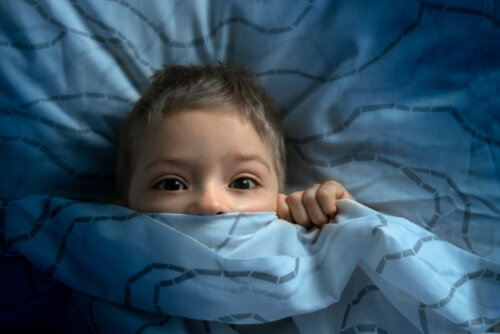 Niño asustado en la cama tras sufrir un episodio de parálisis del sueño.