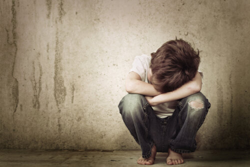 Niño triste sentado en el suelo con mostrando señales de carencia afectiva.