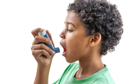 Niño con asma usando un broncodilatador.
