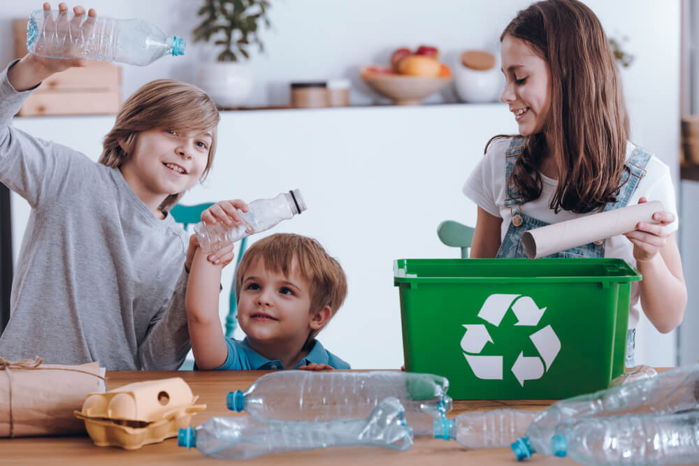Niños reciclando en casa con juegos de reciclaje.
