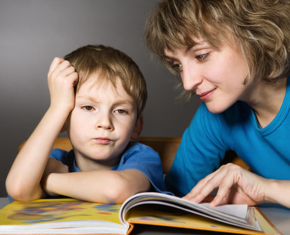 Madre intentando que su hijo aprenda a leer antes de los 6 años.