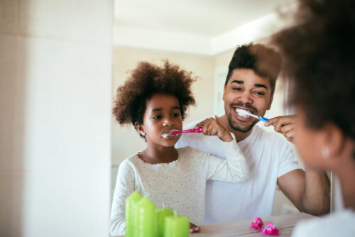 Padre e hija lavándose los dientes para mantener la rutina diaria.