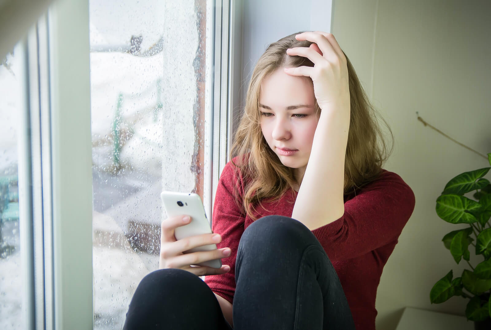 Adolescente con el móvil de la mano sufriendo el síndrome del adolescente normal.