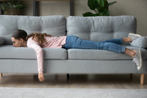 Adolescente tumbada en el sofá sin motivación sufriendo una regresión durante la pandemia.