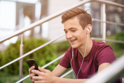 Adolescent consultant les médias sociaux et souriant.