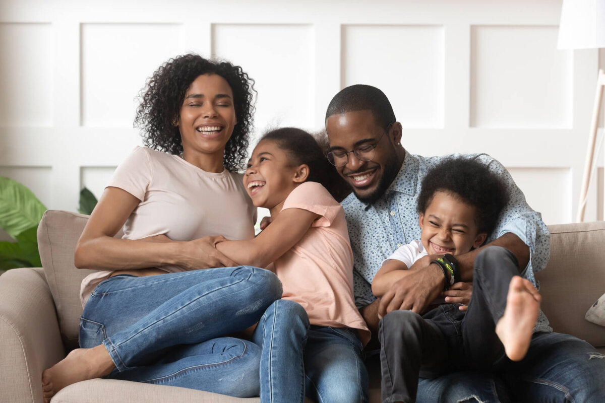 Familia resiliente riéndose en el sofá de casa.