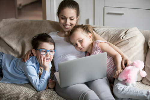 Madre viendo con sus hijos una película en el ordenados y deseando la salud de sus hijos.