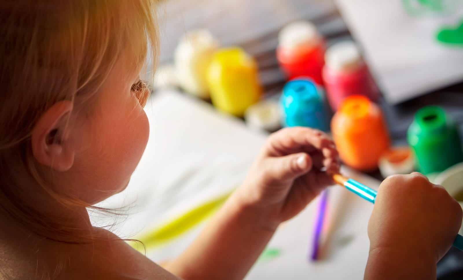 A little girl holding a paintbrush.