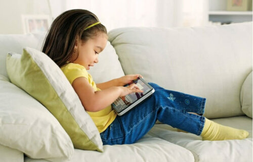 Niña jugando con la tablet para aprender ortografía.