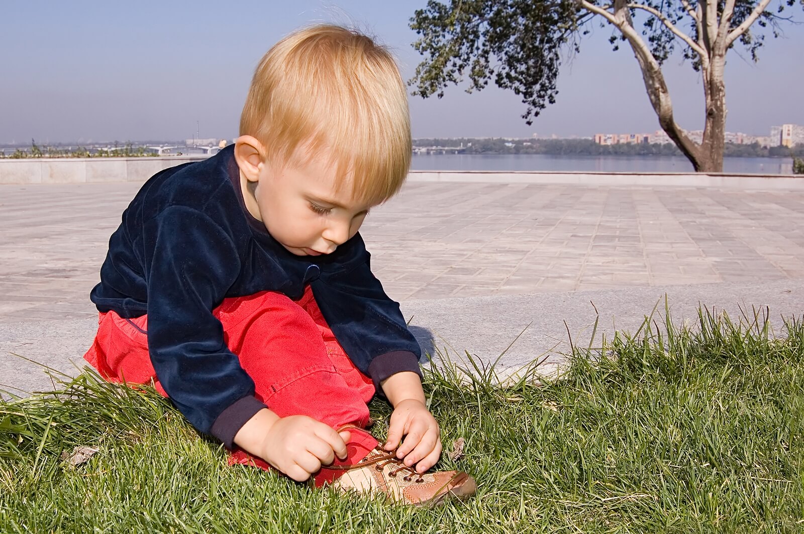 Niño aprendiendo a atarse los cordones de los zapatos gracias a la autogestión del aprendizaje.