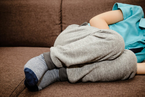 Niño con dolor abdominal tumbado en el sofá.