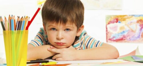 Niño pensativo mientras dibuja y pinta.
