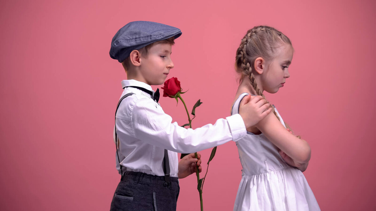 Niño pidiendo perdón a su amiga con una rosa en la mano.