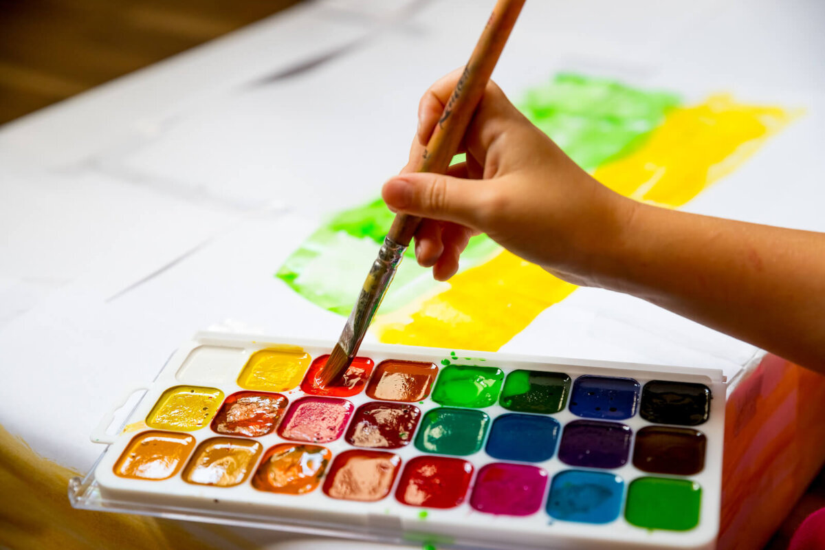 Niño pintando con acuarelas usando algunas técnicas divertidas de dibujo.