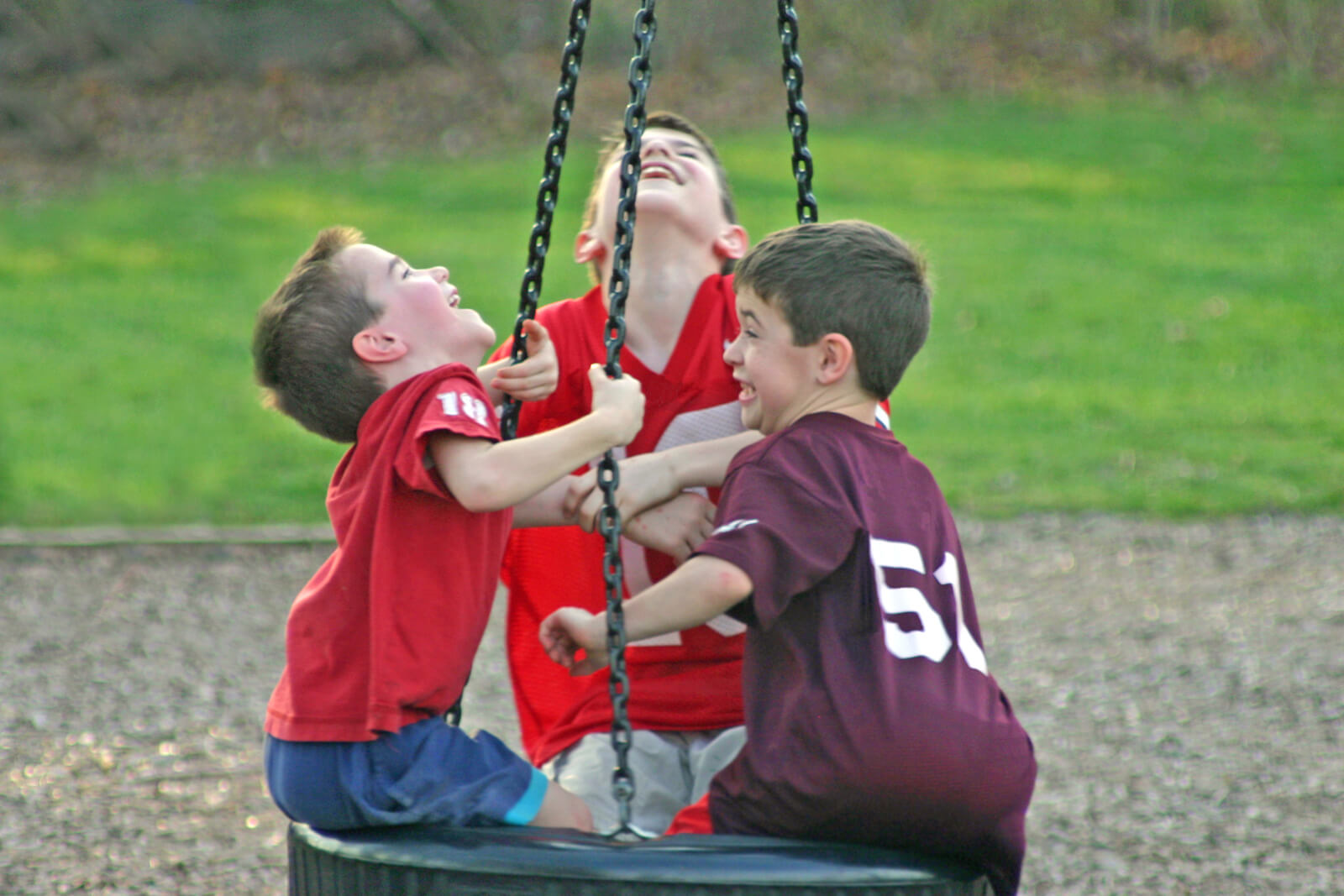 Meninos brincando em um balanço em forma de roda no parque.