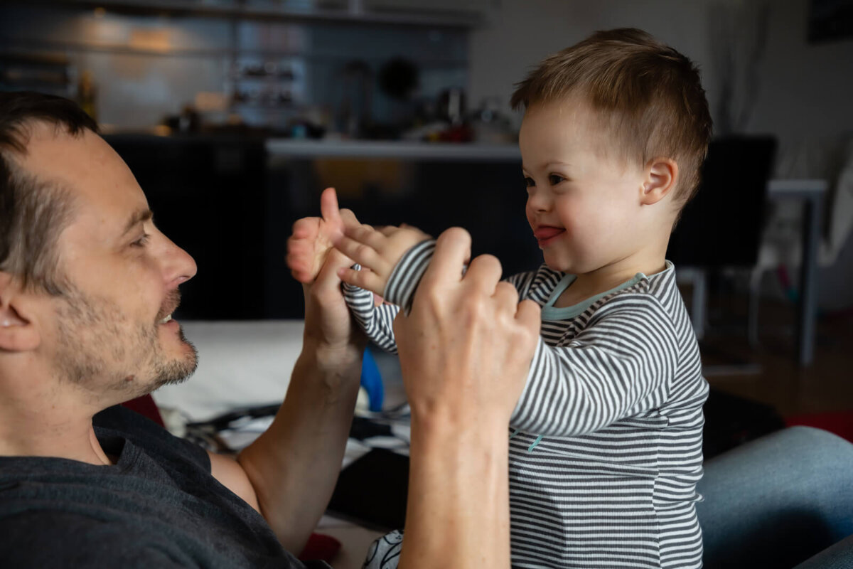 Papá jugando a juegos de estimulación temprana con su hijo con discapacidad intelectual.