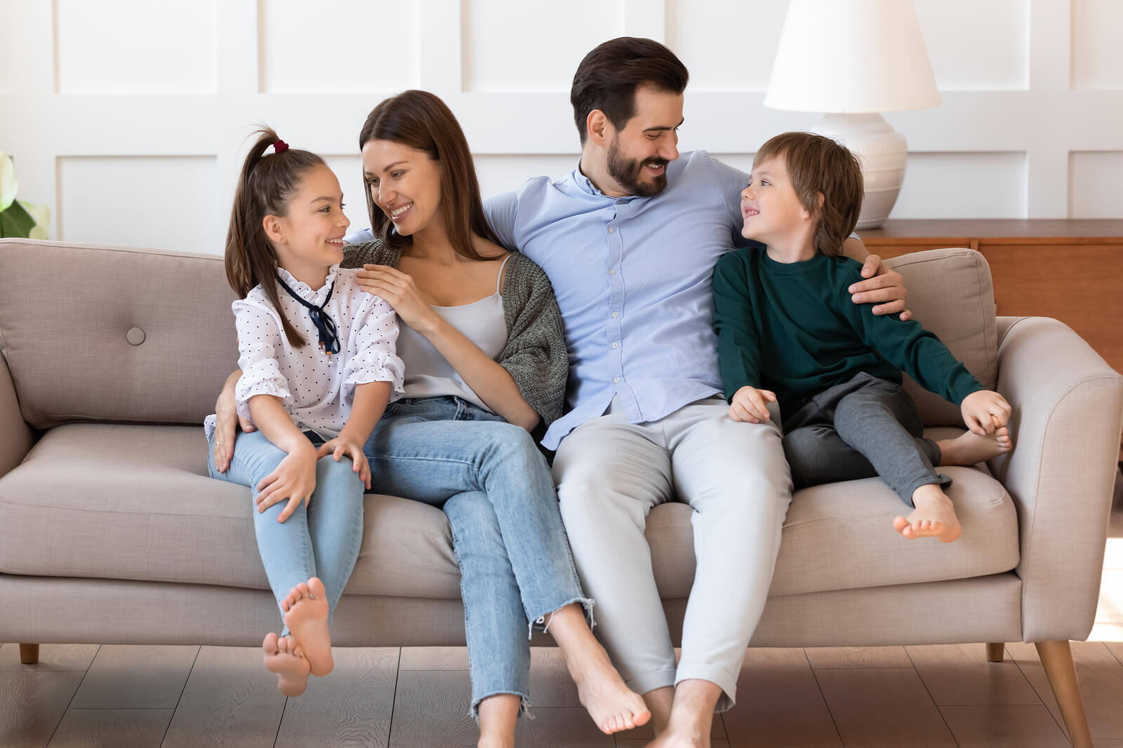 Padres llenado de afecto a sus hijos en el sofá de casa.