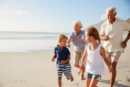 Abuelos y nietos corriendo por la playa.