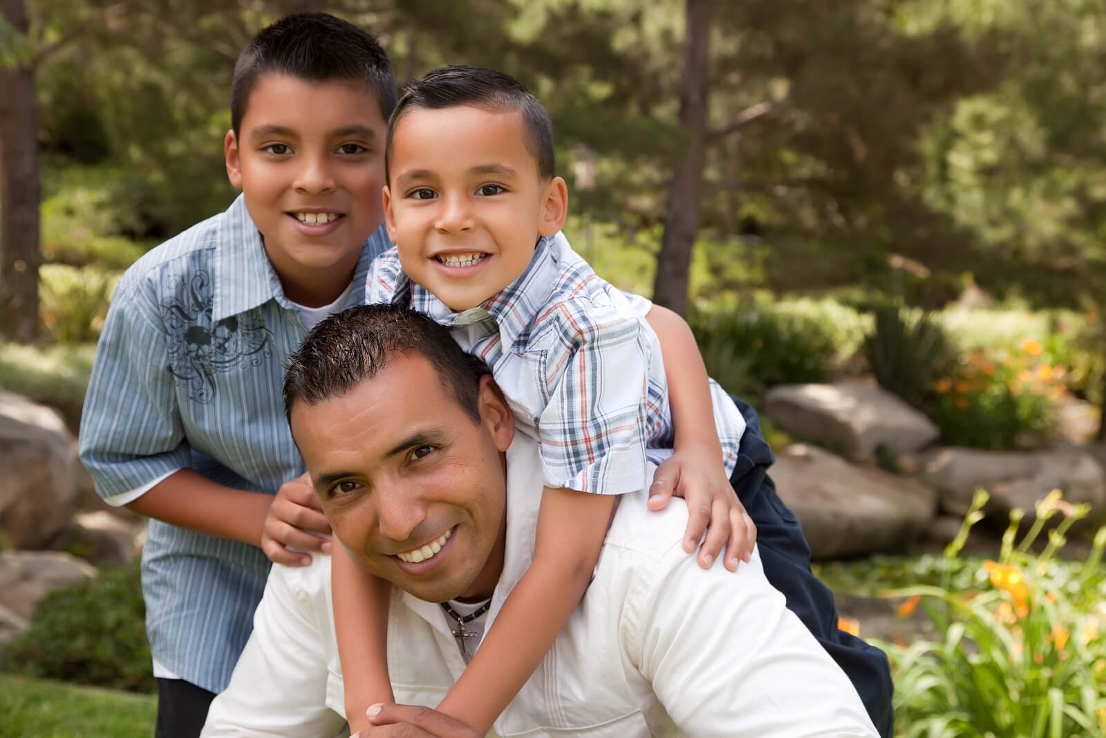 Hijos abrazando a su padre en medio de la naturaleza debido a la importancia del contacto físico en la educación de los hijos.