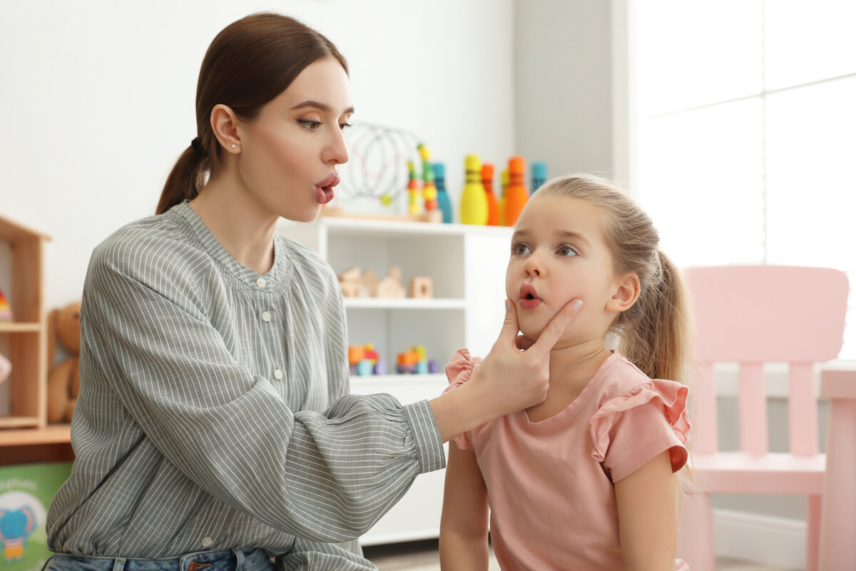 Logopeda trabajando con una niña haciendo praxias.