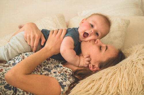 Mamá besando y abrazando a su bebé agradecida por el caos de la maternidad.