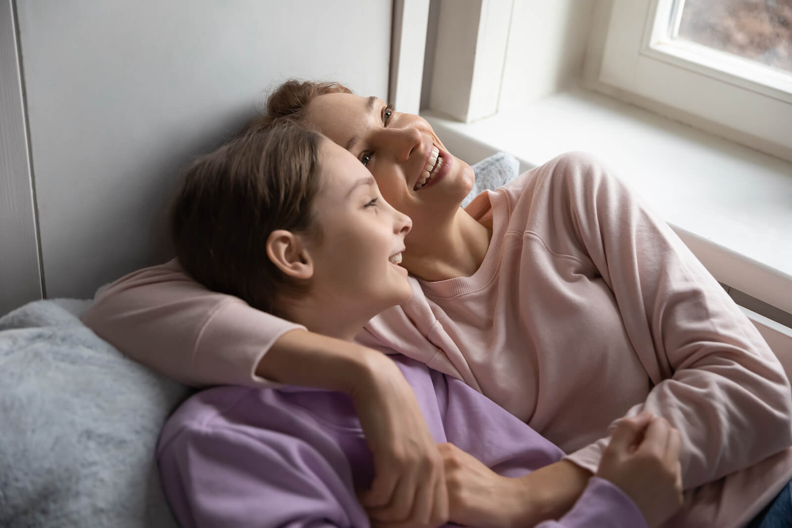 Madre e hija hablando cosas difíciles pero sonriendo.