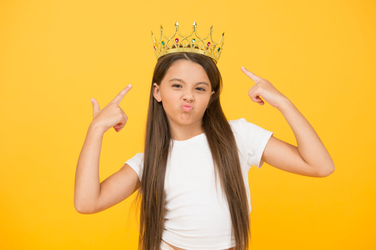 Niña con una corona en la cabeza mostrando su egocentrismo.