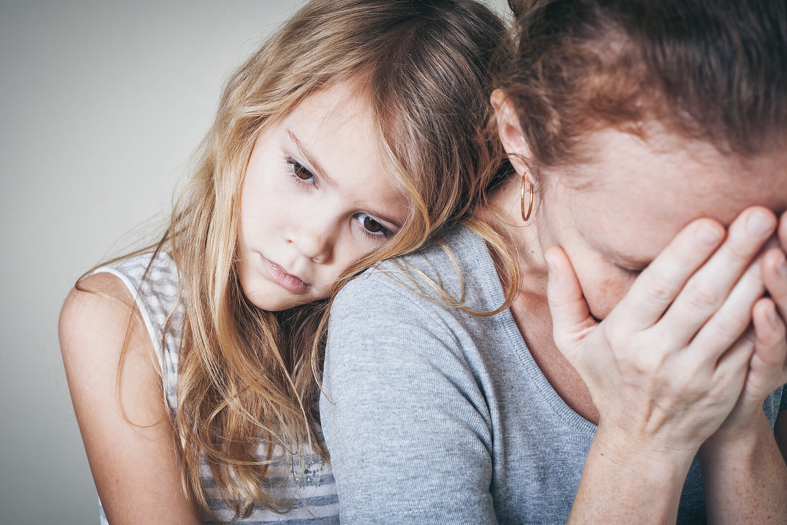 Hija apoya en el hombro de su madre para darle apoyo mientras sufre un ataque de ansiedad.