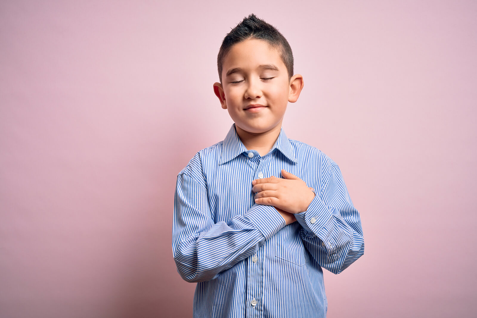 Niño agradecido con las manos en el pecho.