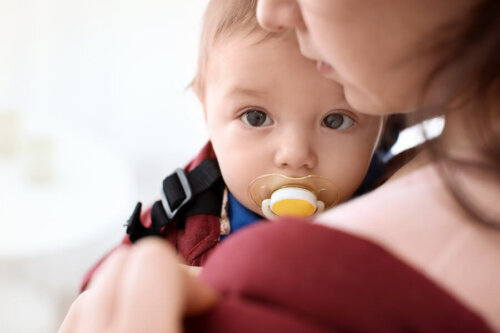 Niño en brazos de su madre con el chupete en la boca.