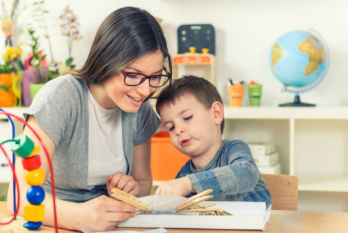 Niño con necesidades de compensación educativa siendo ayudado por su profesora.