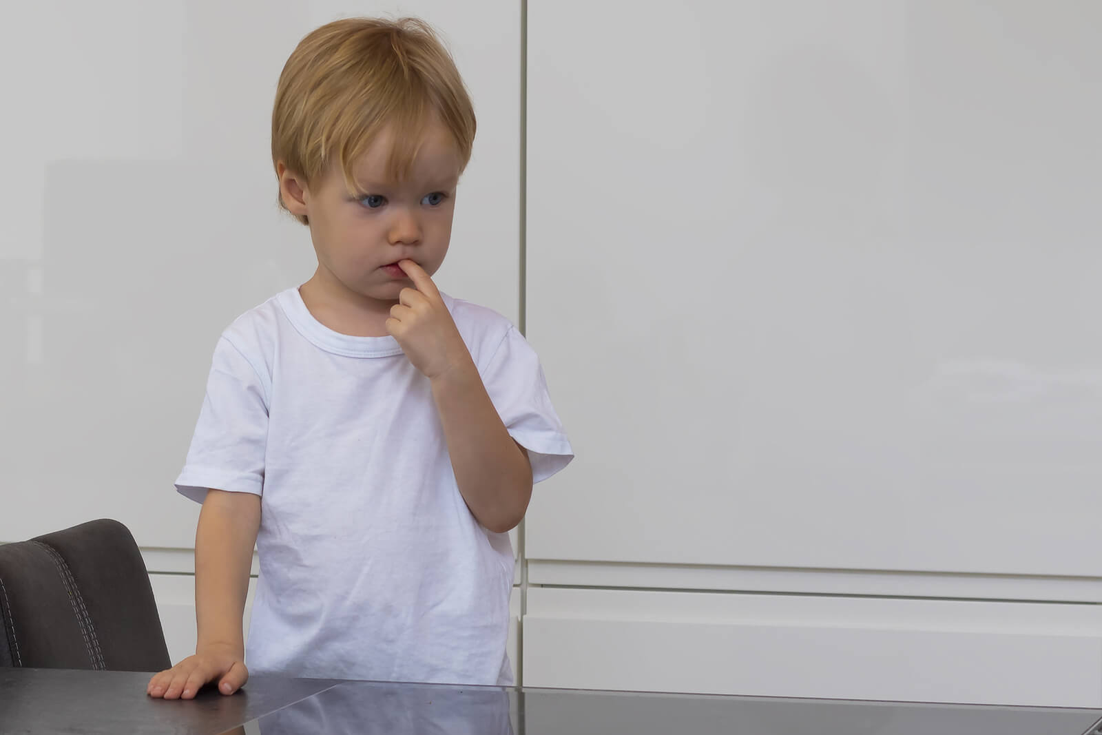 Niño con el dedo en la boca pensando en cómo poner a prueba los límites de sus padres.