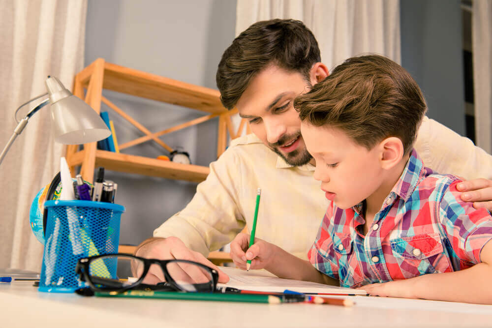 Le père aide son fils à faire ses devoirs scolaires à la maison.
