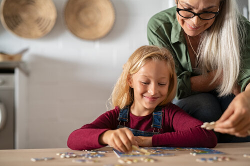 Abuela con su nieta haciendo puzzles para enseñarle a resolver problemas.