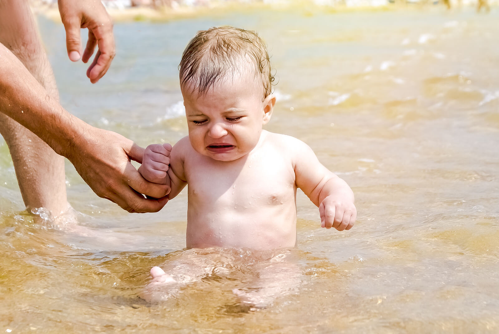 Bebé llorando porque tiene hidrofobia, miedo al agua.