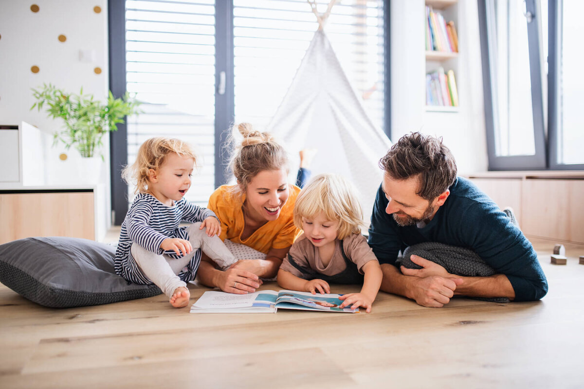 Familia leyendo cuentos breves con valores tumbados en el suelo.