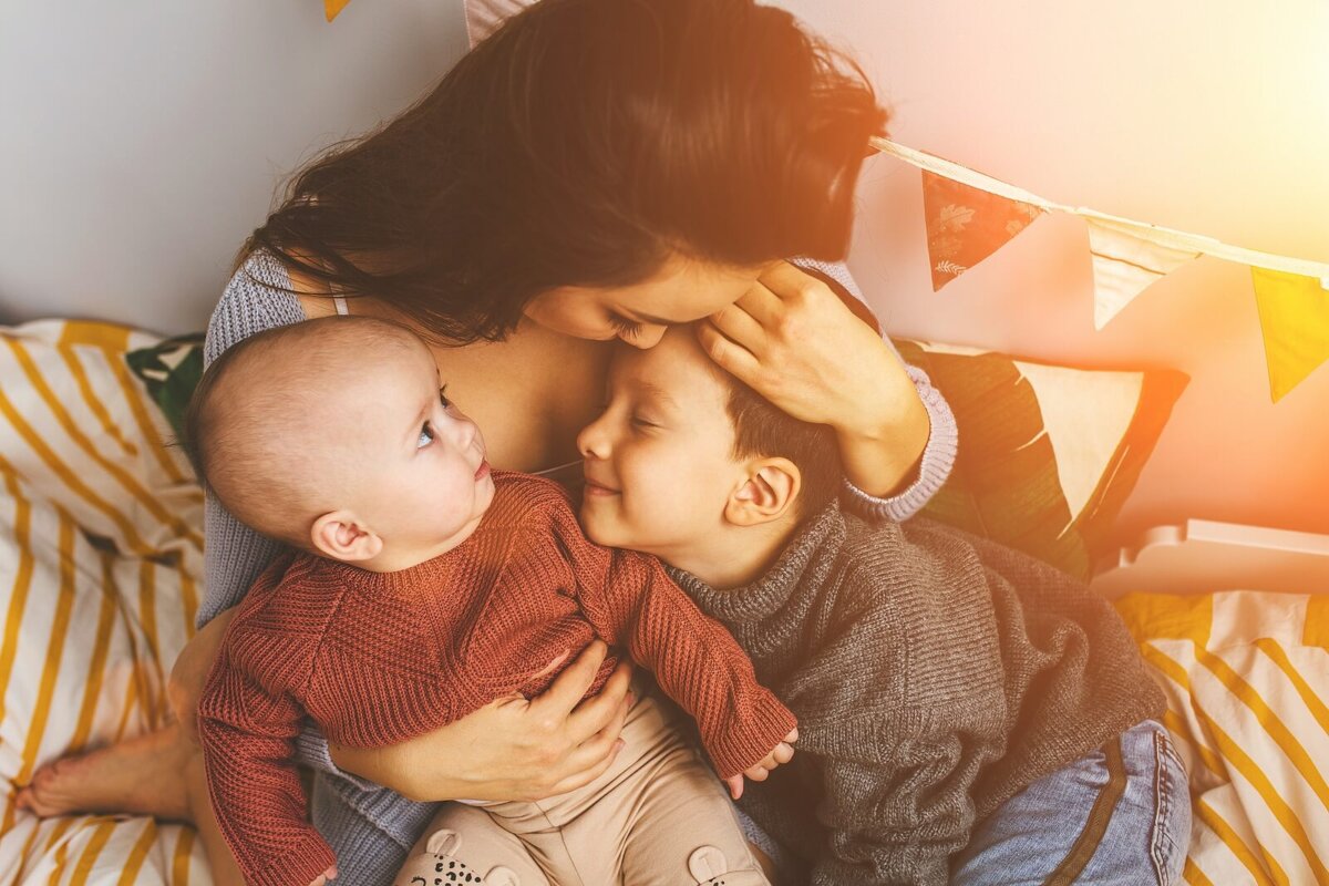 Madre dando besos y abrazos a sus hijos como parte del regalo emocional para su educación.