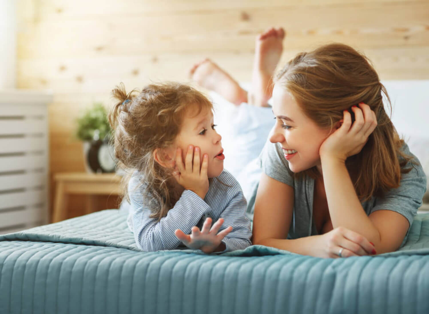 Une maman qui discute avec sa fille sur un lit.