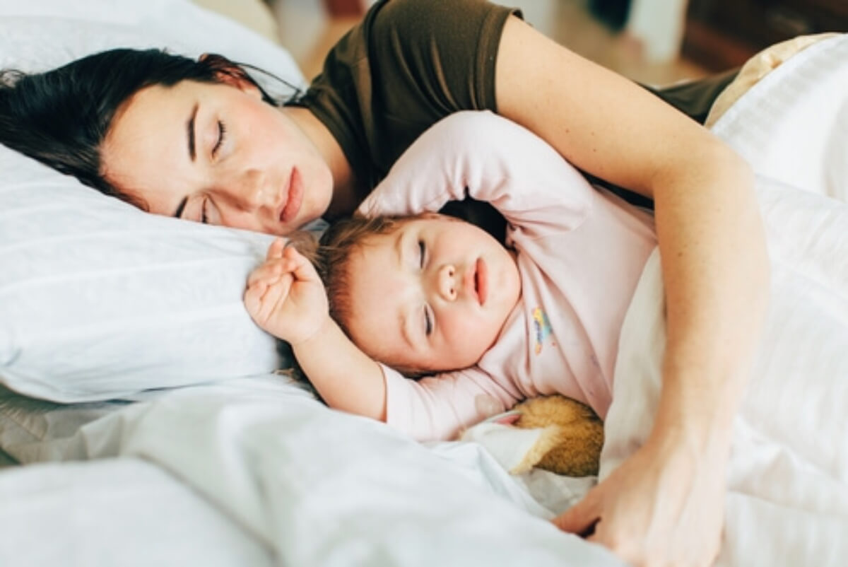 A baby girl cosleeping with her mom.