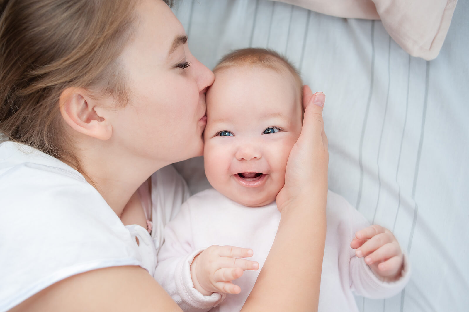 Mom giving her baby a kiss to stimulate him emotionally from birth.