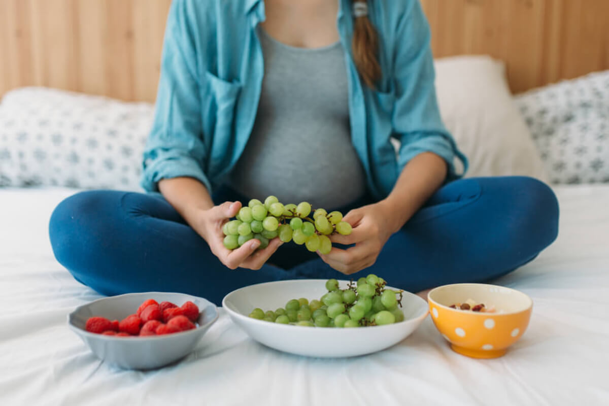 Une femme enceinte qui mange des fruits.