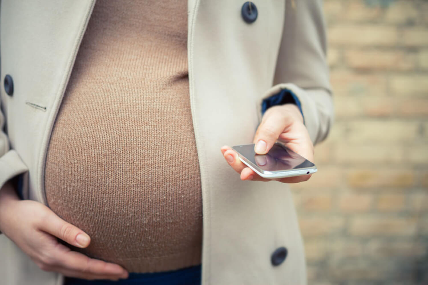 Mujer embarazada con el móvil de la mano.